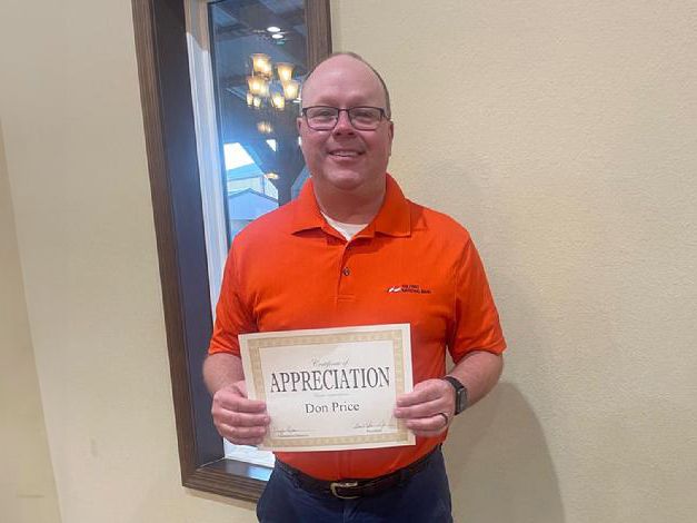 A Man Holding a Certificate in Front of a Wall.