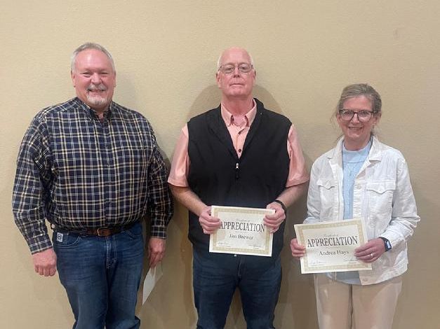 Three Individuals Showing off Their Certificates by a Wall.