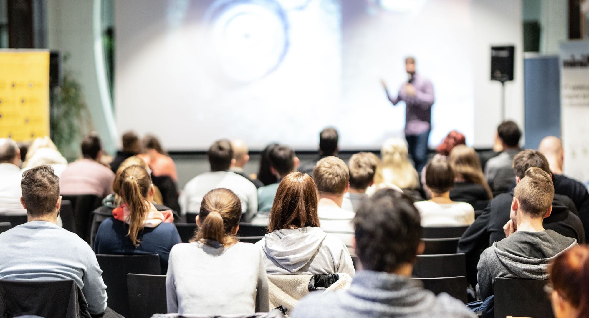 A Man Presenting to a Group of People in a Conference Room.