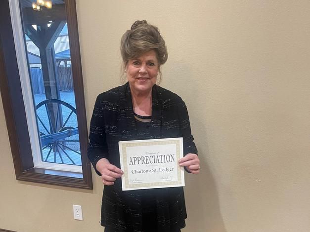 A Woman Holding a Certificate in Front of a Wall.